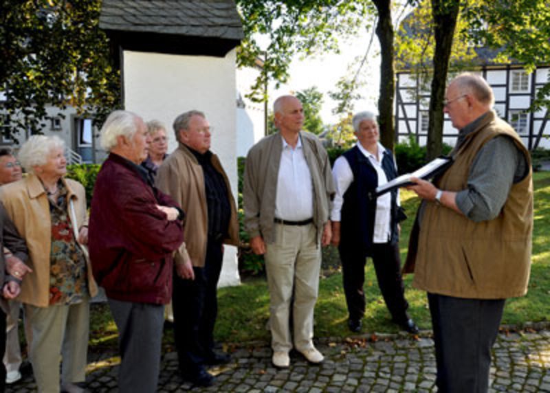 Günter Risse erläutert einer Gruppe auf dem Hirschberger Kirchplatz Wissenswerten zum Thema Hirschberg